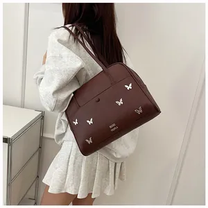 Vue détaillée des papillons argentés sur un sac fourre-tout en cuir marron foncé