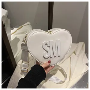 Detailed macro of white heart-shaped leather bag with SM logo and gold metal hardware