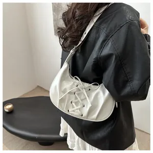Detalle del bolso de media luna blanco con cordones tipo corsé y textura de cuero plisado