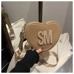 Detail of heart-shaped khaki crossbody bag with 3D SM letters and wide woven strap