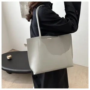Détail d'un sac cabas minimaliste gris avec de fines bandoulières et décor en métal