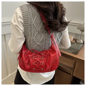 Detalle del bolso hobo de PU rojo con cordones decorativos cruzados y un lazo elegante
