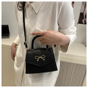 Detail of black mini handbag with gold bow hardware and elegant leather texture
