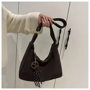 Detalle del bolso tote marrón mate con colgante de pretzel y borla de rayas moderno