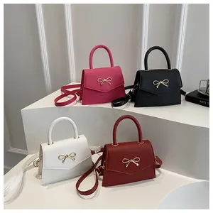 Mini bow handbags in rose pink, black, white, and wine red colors on a white pedestal