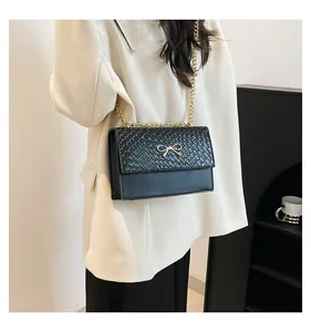 Close-up of black PU leather bag with golden metal bow and scale-textured pattern detail
