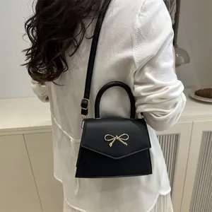 Elegant black envelope handbag with a golden metal bow and versatile crossbody strap