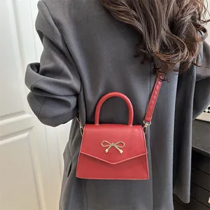 Red bow crossbody square bag with gold buckle on gray blazer outfit for women