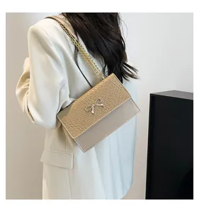 Detail of beige faux leather bag with crocodile pattern and golden bow buckle