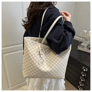 Detailed side view of tote bag with M-pattern print and metallic silver charm