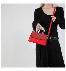 Macro detail of red rectangular handbag featuring glitter texture and silver metal handle