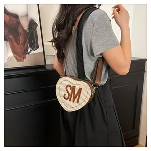 Detail of heart-shaped straw crossbody bag with SM letter patch and wide strap