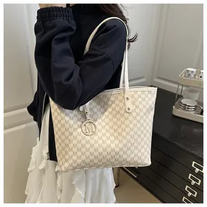 Detail of minimalist tote bag with monogram print and metallic logo charm accessory