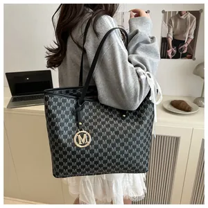 Detailed close-up of dark grey tote bag with monogram patterns and golden M pendant