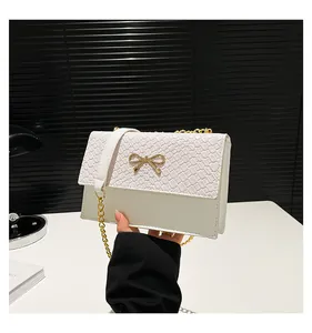Close-up of elegant white woven texture bag featuring a golden bow-shaped metal buckle