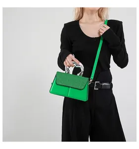 Detail of lime green crossbody bag with sculptural silver metal handle and grainy texture