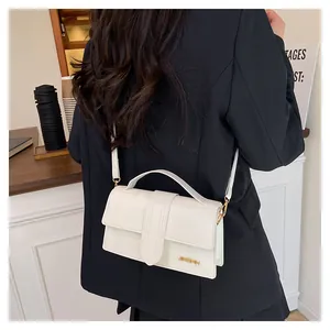 Dettaglio di una borsa a tracolla rettangolare bianca con logo dorato e trama in pelle fine