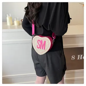 Detail of heart-shaped woven crossbody bag with pink SM embroidery and adjustable strap