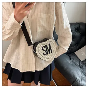 Detail of heart-shaped crossbody bag featuring woven texture and SM letter applique