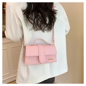 Dettaglio della borsa a tracolla rosa con logo dorato e cinturino sottile chic