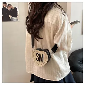 Detail of heart-shaped beige woven crossbody bag with black SM letter and wide strap