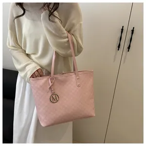 Close-up of pink tote bag featuring letter monogram pattern and gold M-logo pendant