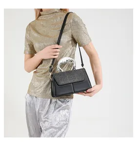 Detail of black crossbody bag with shimmering sequins and silver metallic curved handle