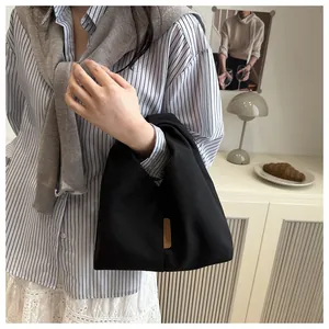Détail de la texture du sac cabas en velours noir avec étiquette en cuir à la mode