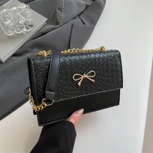 Elegant black bow crossbody bag with snake-embossed flap and gold chain strap for women