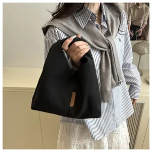Détail du sac fourre-tout en velours noir montrant l'étiquette en cuir et la texture du tissu