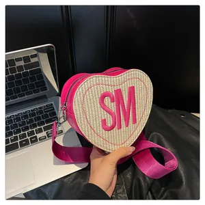Detail of heart-shaped woven crossbody bag with pink leather trim and SM embroidery