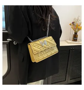 Detail of gold quilted chain bag with silver butterfly and metallic finish texture