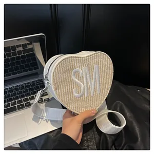 Detail of heart-shaped crossbody bag with SM embroidery and woven texture