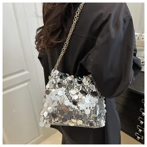 Detail shot of sparkling silver sequin handbag with elegant gold chain strap worn by model