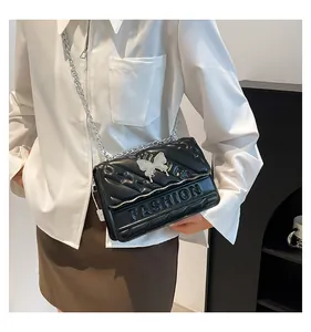 Detail of black quilted bag with silver butterfly metal piece and chain strap