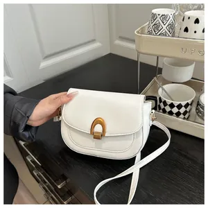 Détail du sac selle blanc avec fermoir en bronze vintage et bandoulière réglable