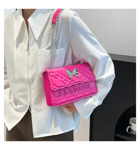 Detail of hot pink quilted crossbody bag with silver butterfly and chain strap