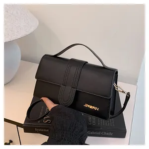 Dettaglio della borsa squadrata nera opaca con logo dorato e cuciture verticali