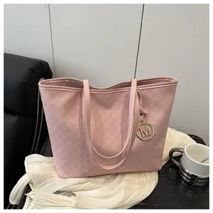 Detailed view of pink tote bag with M monogram pattern and golden metal logo charm