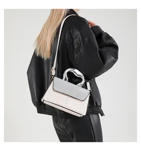 Detail of trendy crossbody bag with sparkling rhinestones and unique wavy metal handle