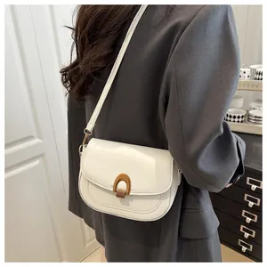 Détail du sac selle blanc avec boucle en U bronze sur une veste de costume