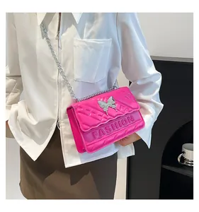 Close-up of bright pink quilted crossbody bag with silver butterfly clasp and chain strap