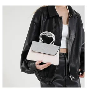 Detail of trendy small square bag featuring rhinestone flap and twisted silver handle