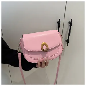 Détail d'un sac besace rose avec boucle dorée en U et finitions de couture de haute qualité