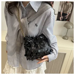 Detail shot of the black sequined crossbody bag featuring a golden metal chain strap