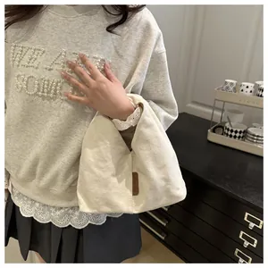 Détail du sac cabas en toile crème avec étiquette en cuir marron et poignée minimaliste