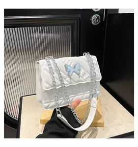 Macro shot of white quilted leather bag featuring a light blue 3D butterfly metal ornament