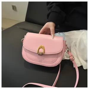 Détail d'un sac besace rose clair avec boucle fer à cheval dorée et texture mate