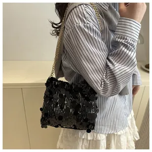 Macro shot of shimmering black sequins and elegant gold metal chain on a shoulder bag