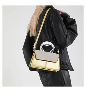 Close-up of metallic gold crossbody bag featuring a unique silver sculptural handle